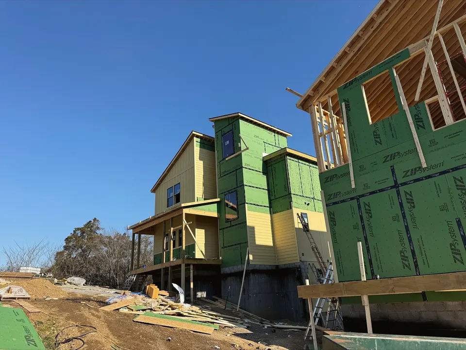 Homes framed and sheathed on an East Tennessee hillside, with building material staged out front