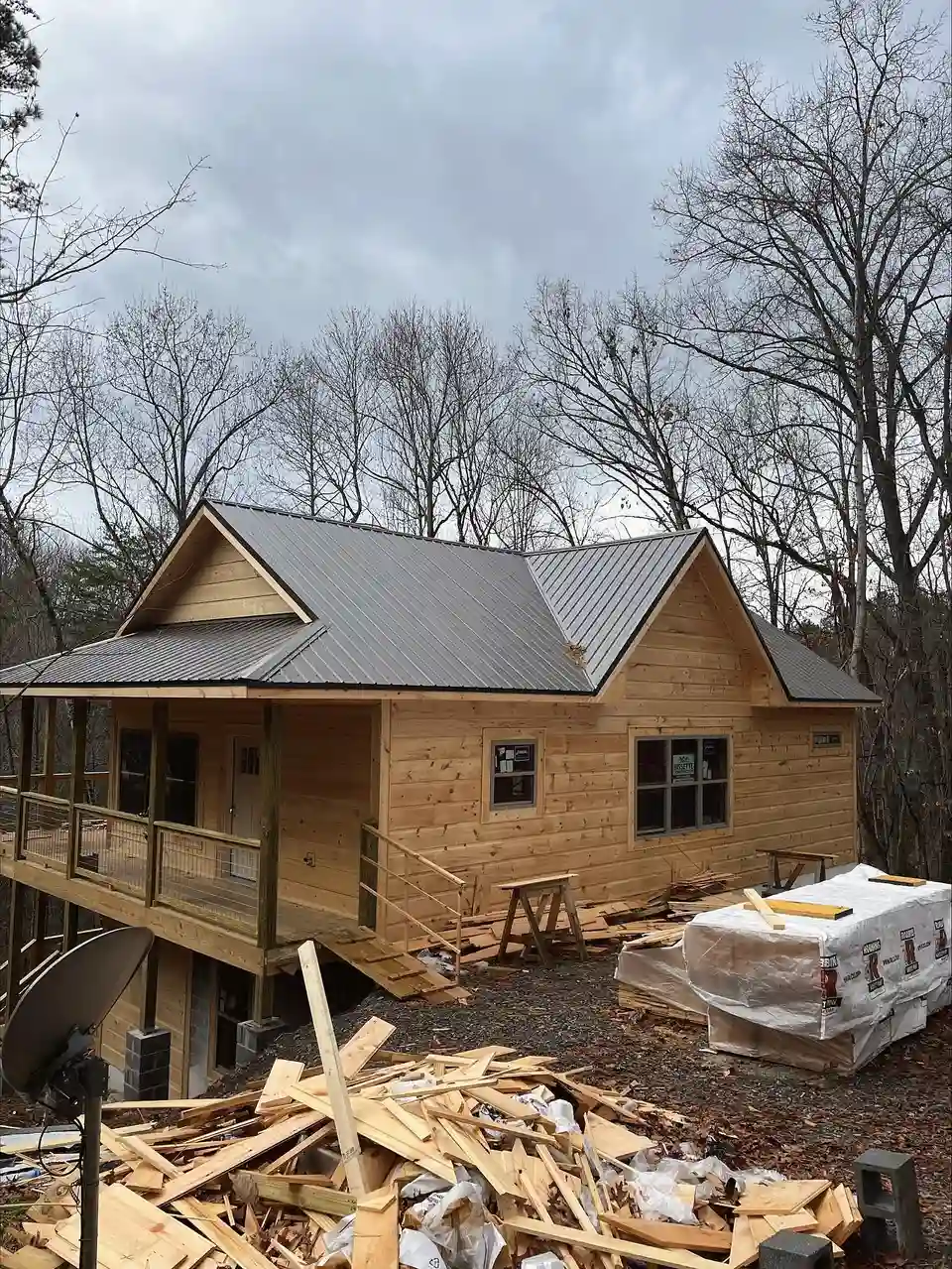 Log-sided cabin with a metal roof and wrapped material packs on site